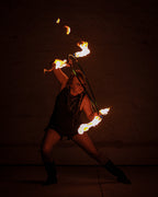 Fire hoop ring with burning wicks, performer holding prop with legs apart.