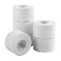 Three white athletic trainer tape rolls, single roll foreground and two stacked back